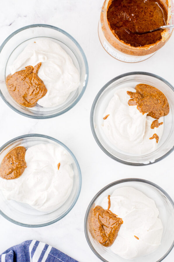 4 serving bowls with a serving of greek yogurt and almond butter in each one.