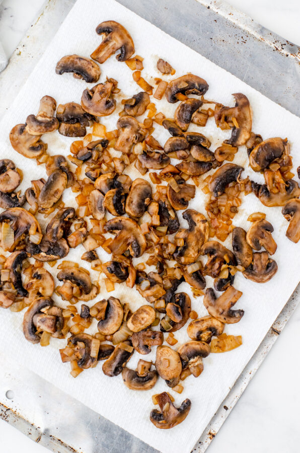 Sauted mushrooms and diced onions on a paper towel lined pan
