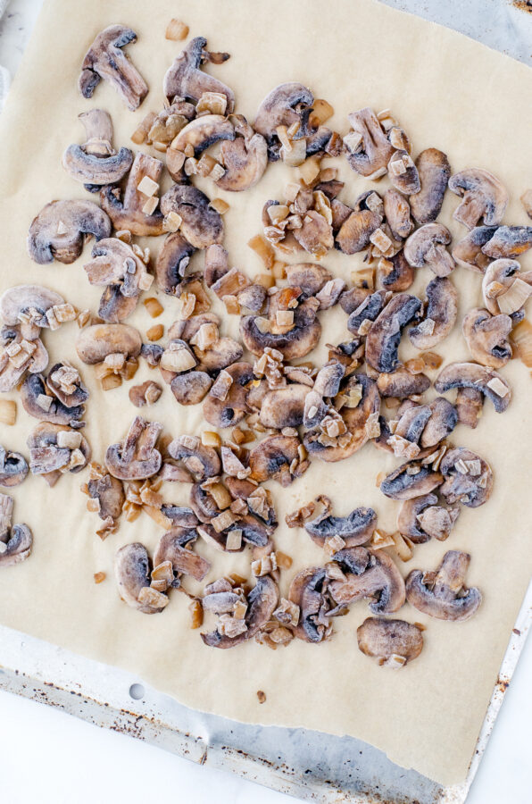 Frozen mushrooms in a single layer on a parchment lined pan.