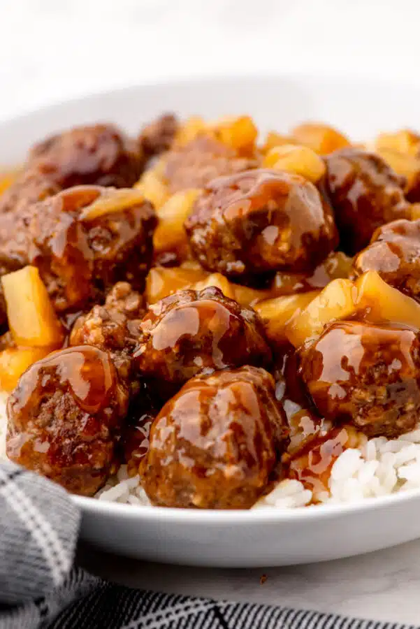 Sweet and sour waikiki meatballs over a bed of rice in a large bowl.