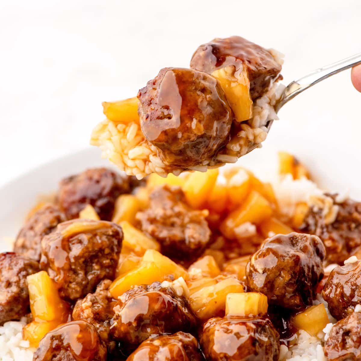 a forkful of sweet and sour waikiki meatballs with pineapple tidbits