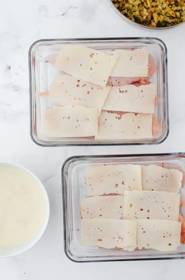 Swiss cheese layered on chicken breasts in a casserole dish.