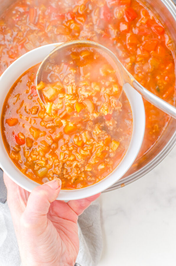 A bowl of hamburger rice soup being dished up.