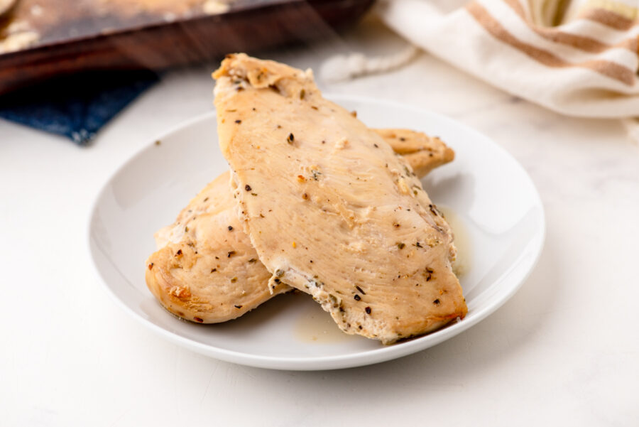 2 pieces of lemon chicken baked and on a serving plate - steaming from the heat.