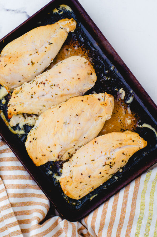 4 chicken breasts that have been marinaded in lemon chicken marinade baked in a stoneware baking pan.