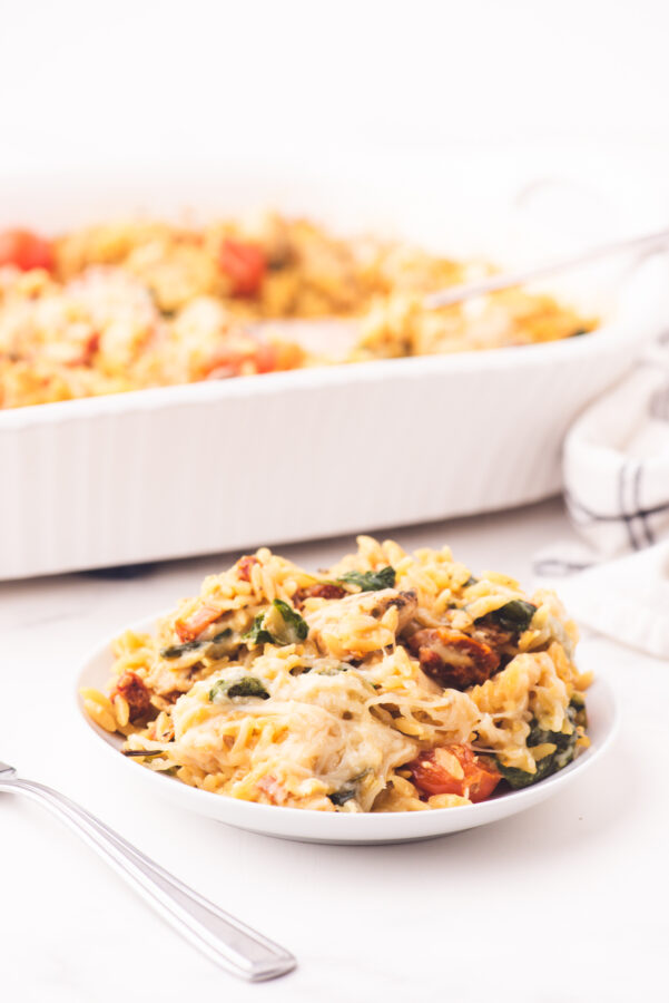 A plate with a serving of chicken orzo casserole on it.
