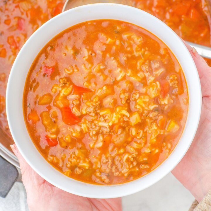 A woman holding a bowl of hamburger rice soup.