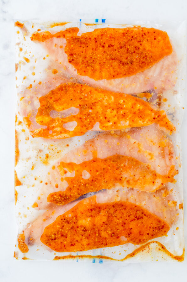 Chicken covered in marinade in a ziploc bag.