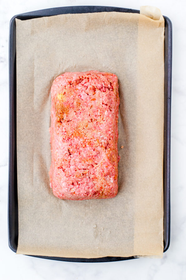 Meatloaf popped out of the loaf pan and on a parchment lined rimmed baking pan,.
