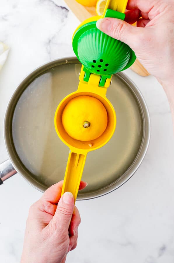 Lemon in lemon juicer over a pot of water for tumeric tea.
