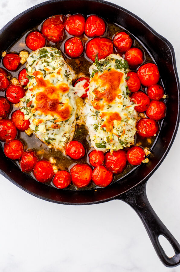 Spinach & feta stuffed hasselback chicken baked over tomatoes in a cast iron pan