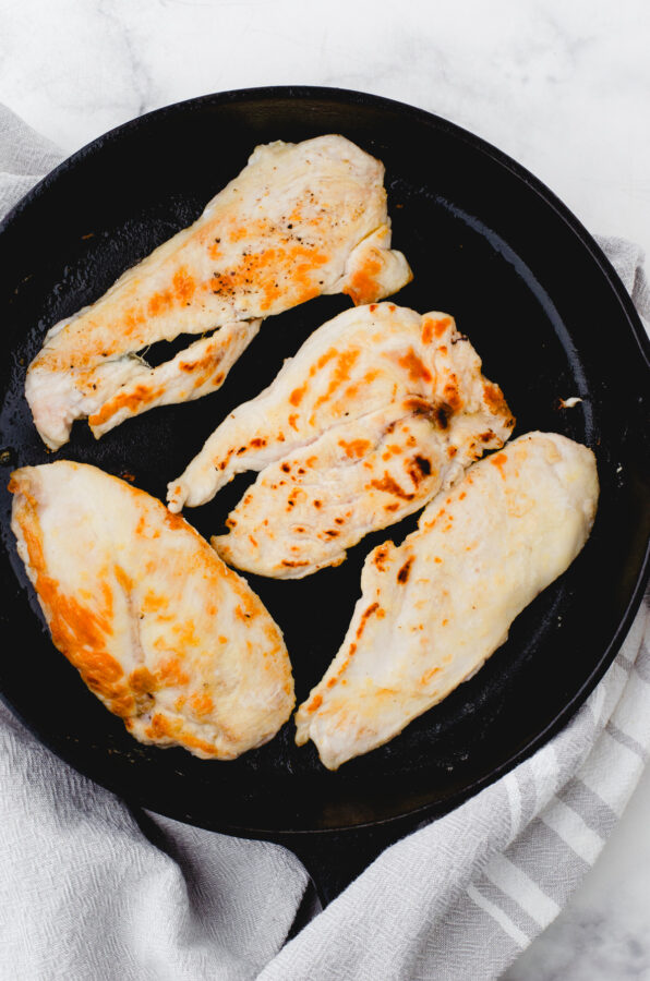 Browned chicken breasts in a cast iron pan.