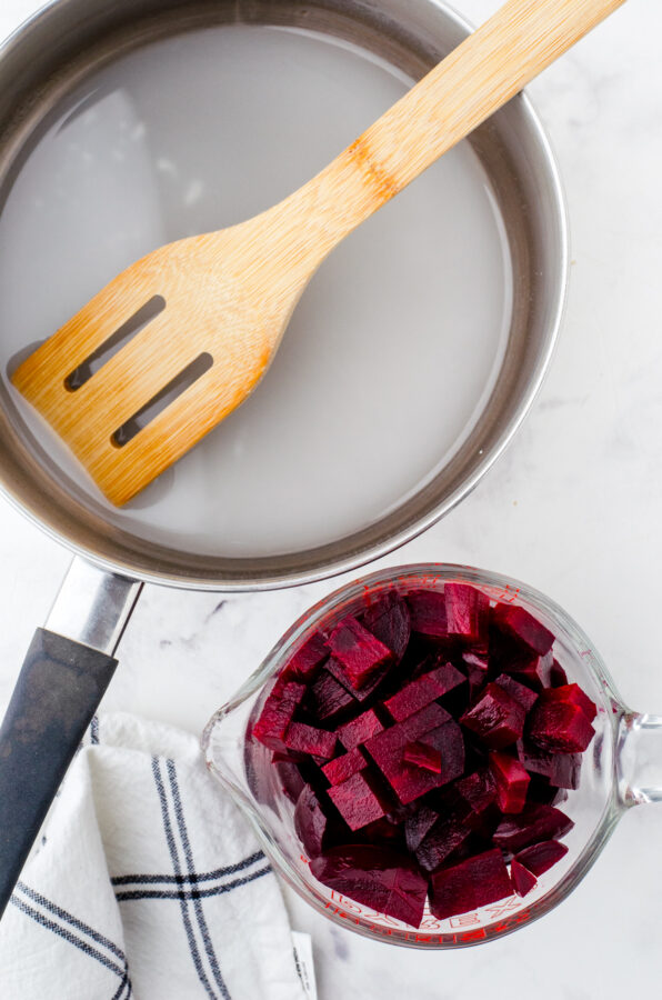 A saucepan with harvard beets sauce ingredients in it with cubed beets beside it.