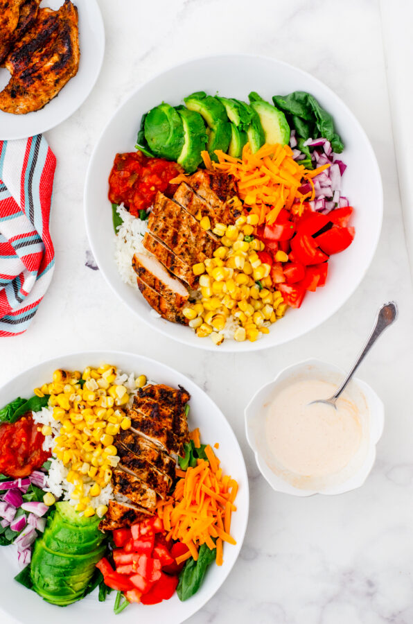 2 bowls of mexican chicken rice bowl with sauce beside