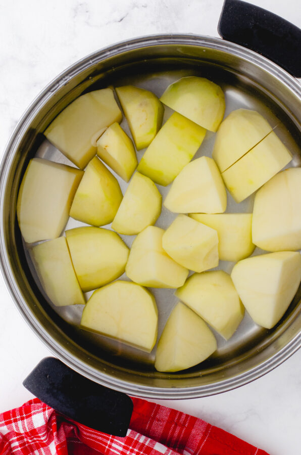Peeleed potatoes in a pot covered with water.
