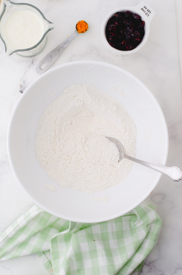 Dry ingredients for cream scones in a mixing bowl being stirred together.