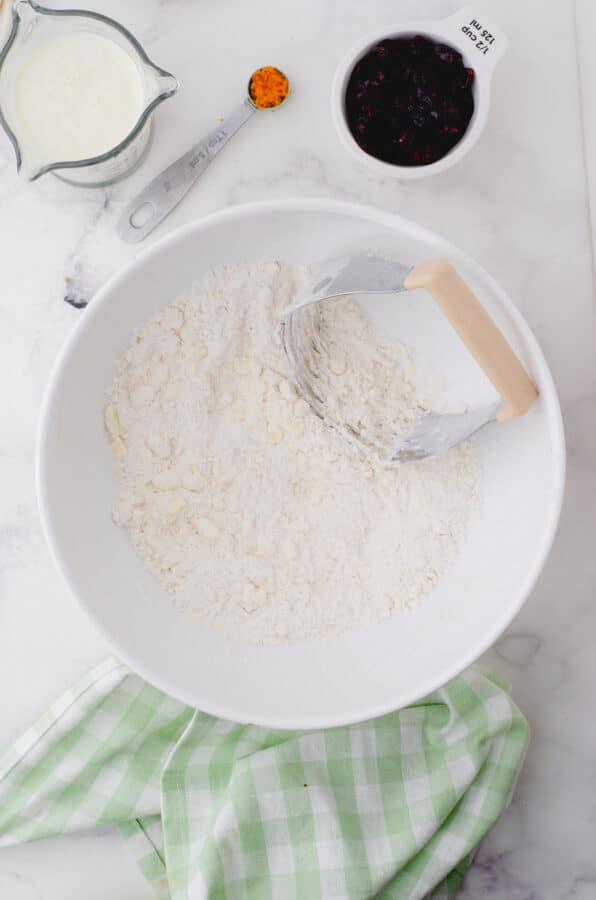 Butter being cut into the dry ingredients with a pastry blender