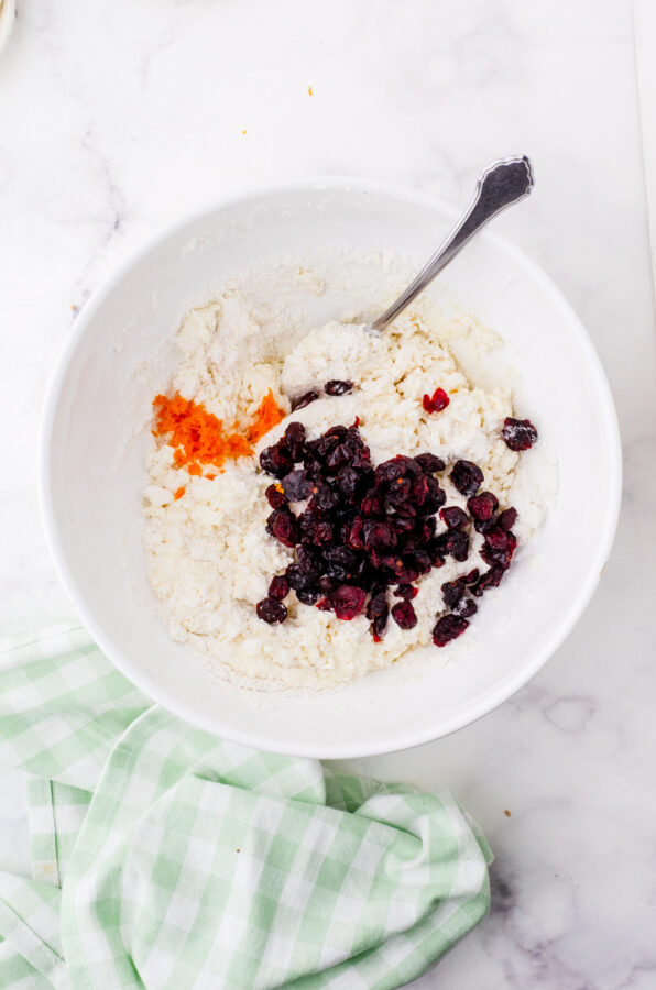 Cranberries and orange peel being added to cream scones.