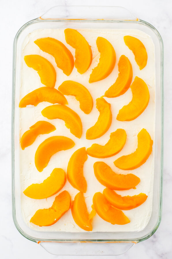 Sliced peaches arranged over cream cheese filling