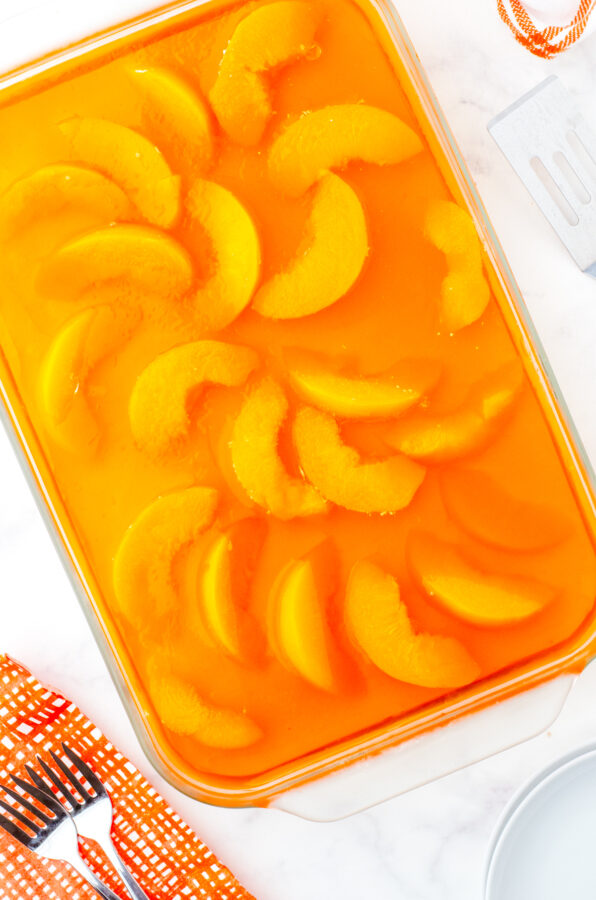 Jello poured over peaches and chilled for peach pretzel salad.