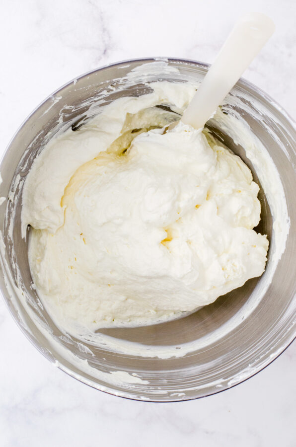 Cool whip being folded into the cream cheese mixer for peach pretzel salad recipe.