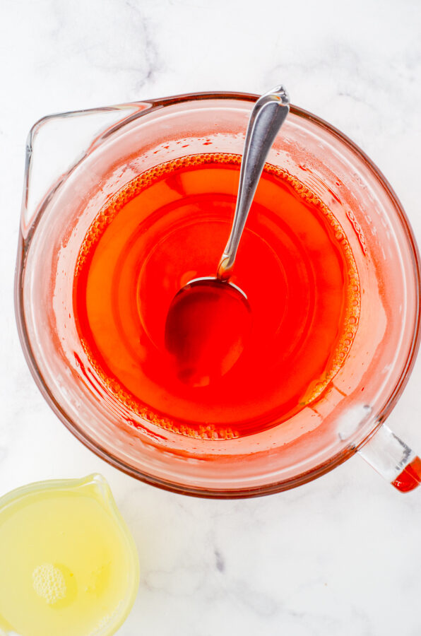 Jello powder being mixed with boiling water with reserved peach juice beside it.