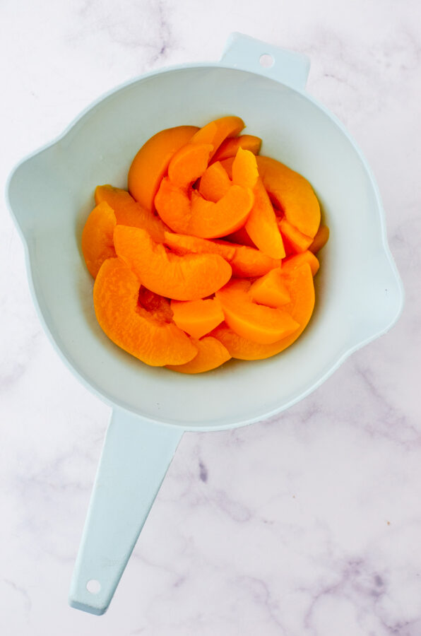 Canned peaches being drained with a strainer