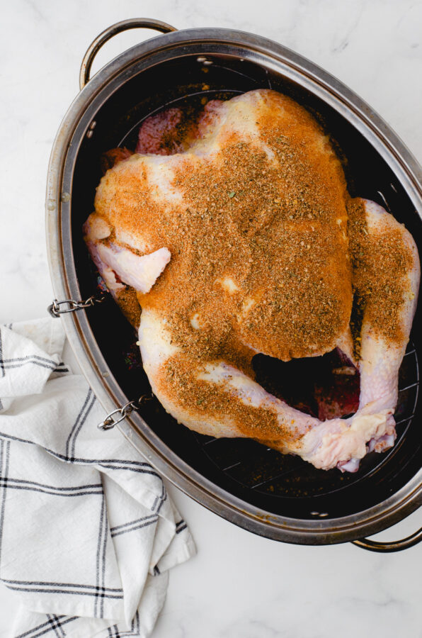 Whole Turkey in roasting pan with spice rub on it.
