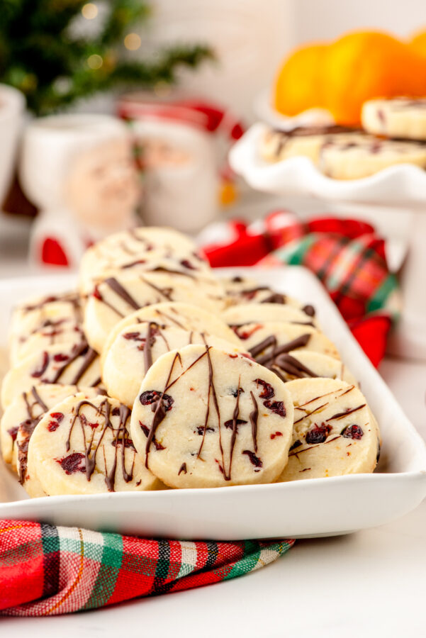 Slice and bake whipped shortbread on a platter with cranberries and a chocolate drizzle.