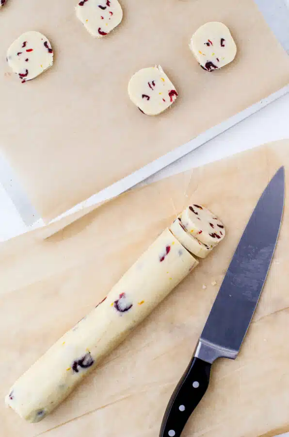 Slices of whipped shortbread cookies being put on baking sheet
