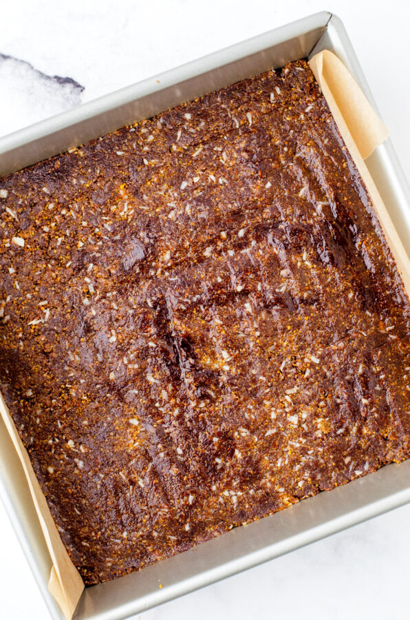 The base layer of nanaimo bars pressed into the bottom of a square pan.
