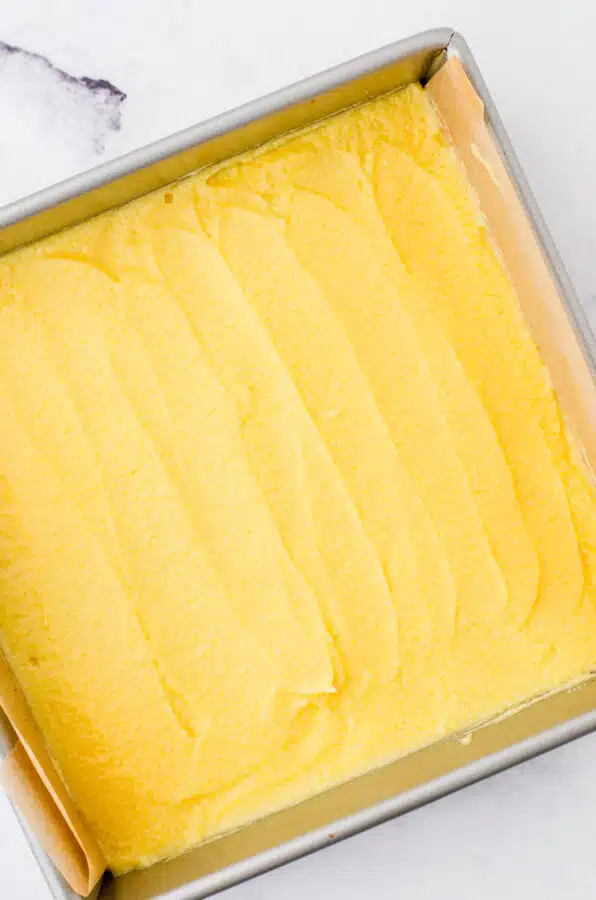 The middle layer of nanaimo bars spread over the bottom layer in a square pan.